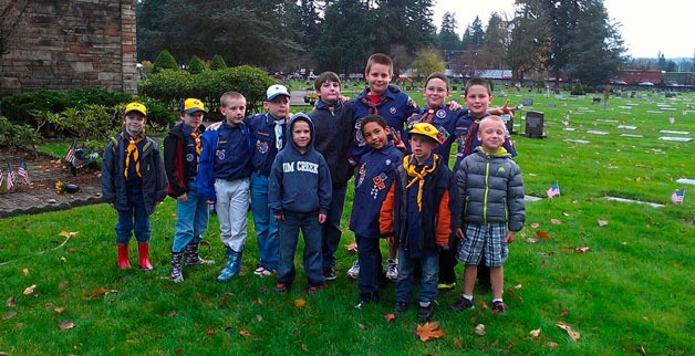 Cub Scout Pack 80 members pause in the midst of placing flags on the headstones of service members in the Marysville Cemetery on Nov. 10. Back row from left