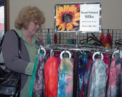 Snohomish’s Penny Goodwin checks out the hand-painted silk scarves of Marysville’s Karen Lyons at the second annual ‘It’s Raining Art’ show and sale on April 27.
