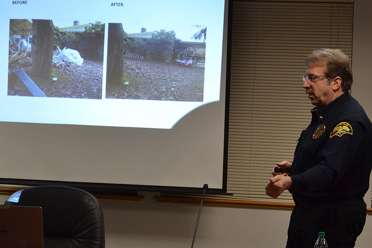 Cmdr. Mark Thomas talks to the City Council about Code Enforcement. On the screen shows a homeowner who voluntarily complied with cleaning up the property.