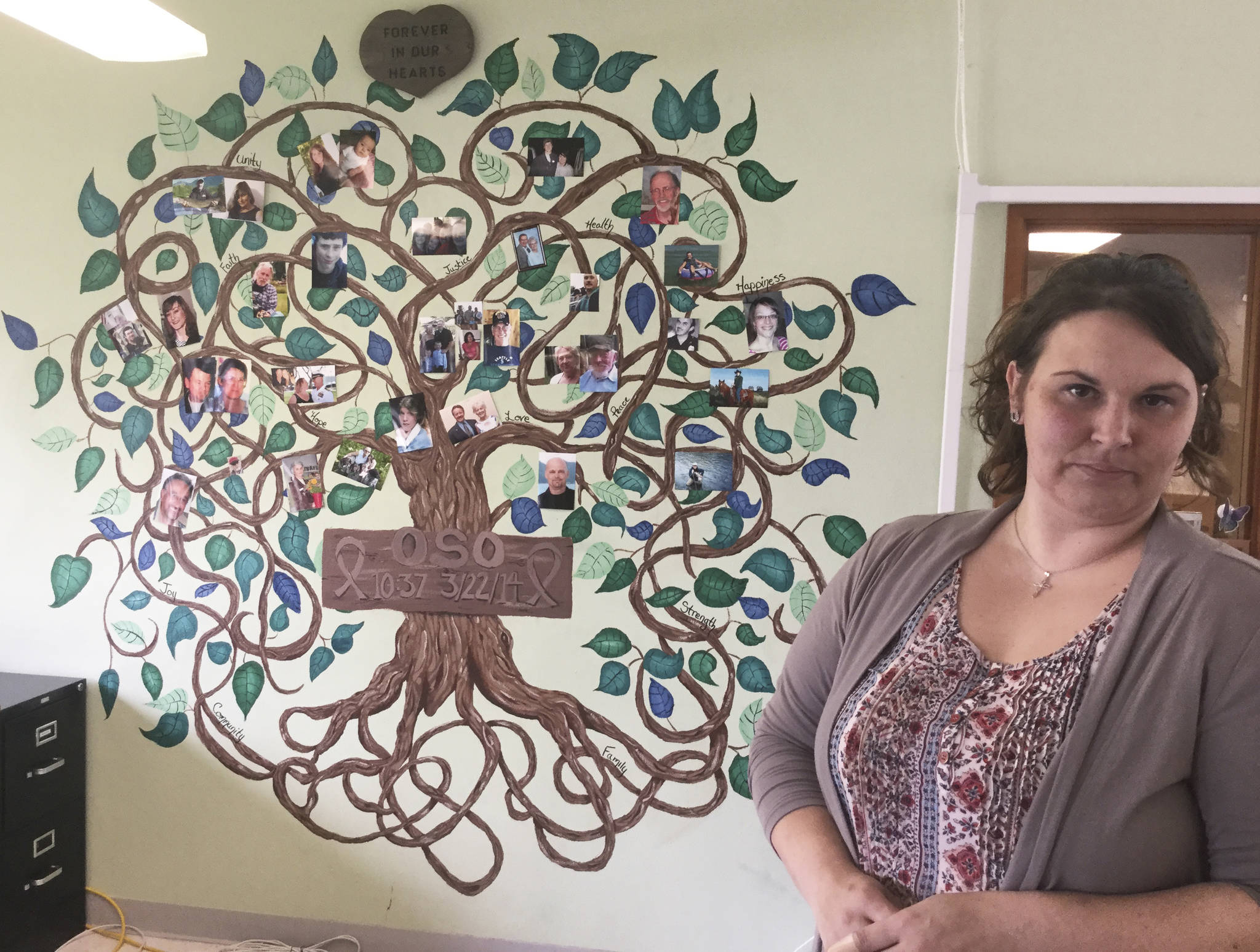 Caroline Neal painted a mural in memory of Oso slide victims, including her father Steve, whose photo appears closest to the Oso sign shown in the painting.