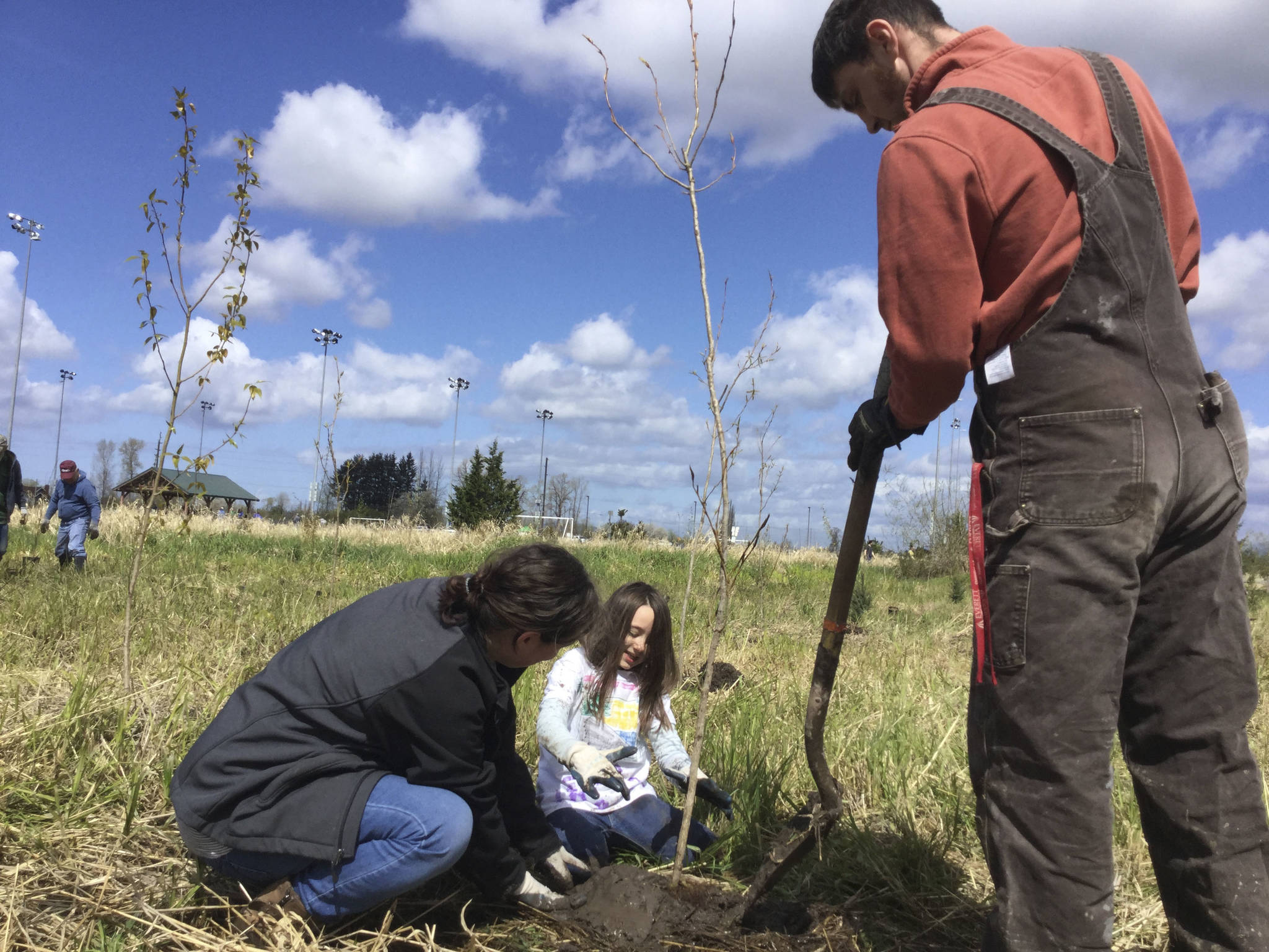 Justine Brock, 7, and her parents Alexa and Josh of Lakewood plant young coniferous trees along the middle fork of Quilceda Creek during an Earth Day event at Strawberry Fields Park in Marysville Saturday.