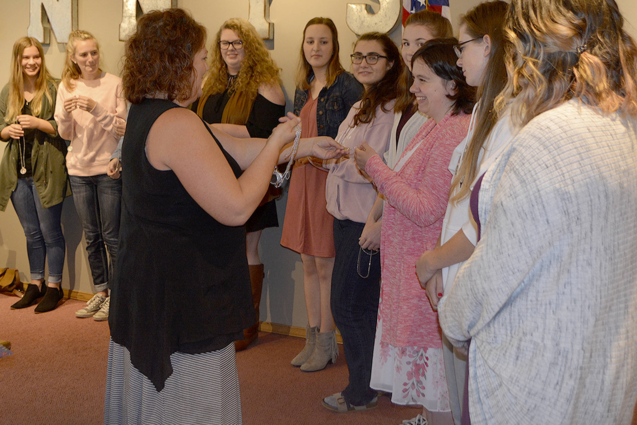 Nancy Schaut hands out “Wonder Woman” necklaces to Marysville high school graduates who received Soroptimist scholarships Tuesday. Schaut won one in 1988 and returned to the club to help the community. (Steve Powell/Staff Photo)