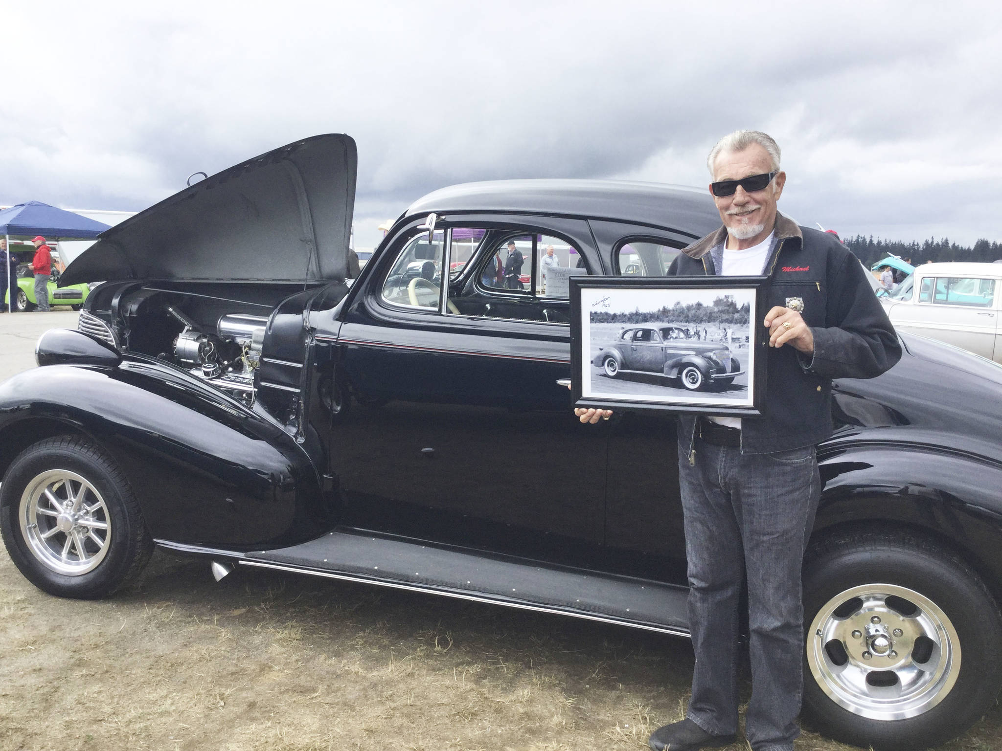 Mike Hayes of Marysville at the Arlington Drag Strip Reunion and Car Show with his restored 1939 Chevy De Luxe, a race car originally owned by legendary drag racer Gentleman Hank Johnson, Jr. Hes holding a old portrait of the car signed by the gentleman himself.