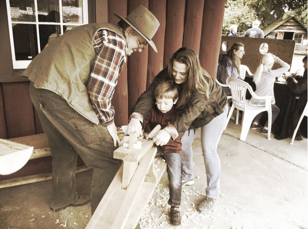 Brad Merritt, of Arlington, gets tips from renowned Arlington woodwright and farmer Bill Pierce from Soaring Swallow Woodworks, with a little extra help from the boy’s grandmother, Christie.
