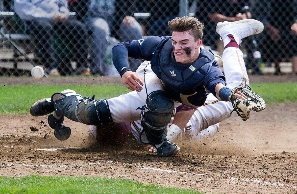 Arlington catcher Jack Sheward gets plowed into at the plate in the loss to O’Dea. (Andy Bronson/The Herald)