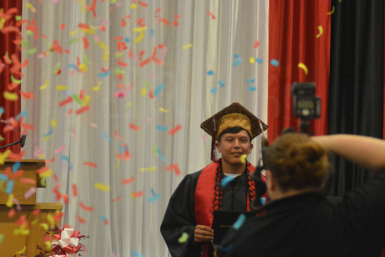 Confetti surrounds Tulalip Heritage graduate Joshua Iukes as he walks off the stage with his diploma.