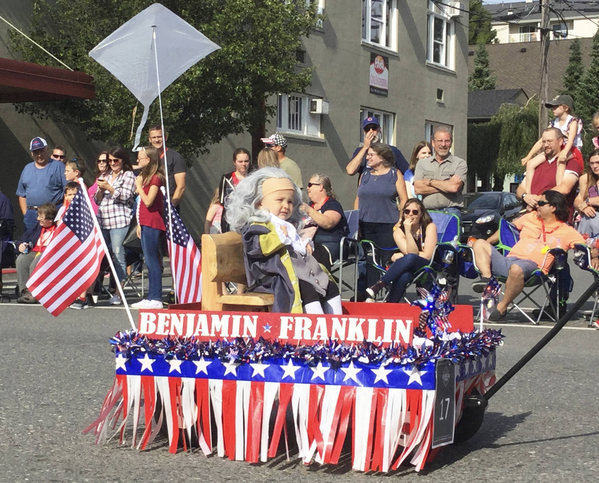 Dressed as a young Benjamin Franklin riding in a patriotic-decorated wagon, 10-month-old Ledger Greenfield of Lake Stevens took first place float honors in Arlingtons Fourth of July Parade. His father, Bob, pulled the wagon down Olympic Avenue donning a one hundred dollar bill costume.