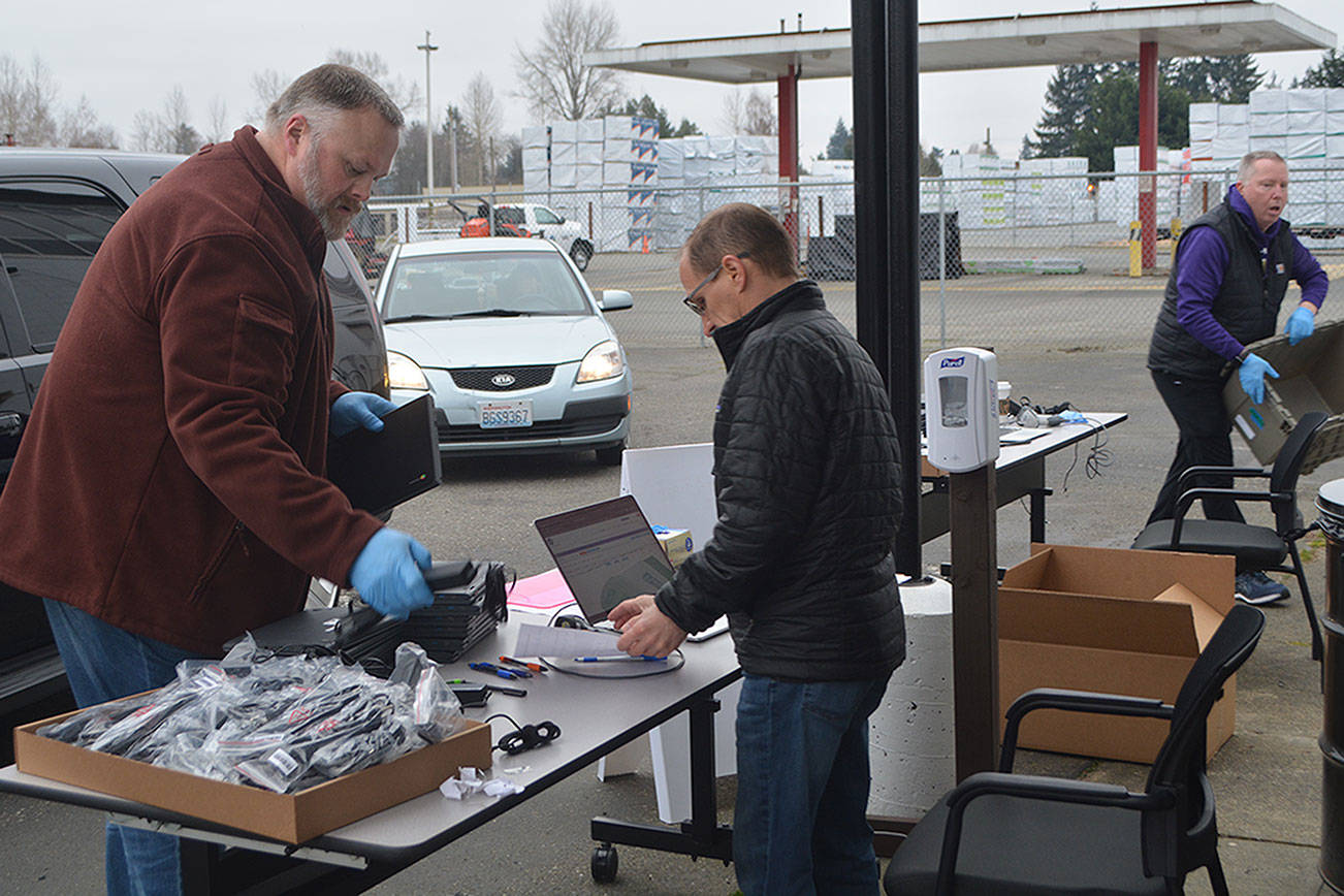 Scott Beebe hands out Chromebooks to people in their cars. (Steve Powell/Staff Photos)